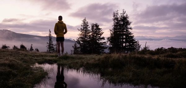 Fešný turista pozoruje západ slunce v modravé alpské krajině Národního parku Vysoké Taury.