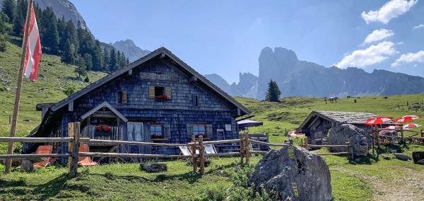 Az autentikus látványt nyújtó Stuhlalm hütte a nyári napsütésben az alpesi hegyekkel körülvéve a Dachstein West régióban
