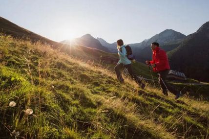 Kényelmes túrázók a a Salzburgi Salachtal alpesi legelőjén napfelkeltekor. Szervezett csomagszállítás a szálláshelyre