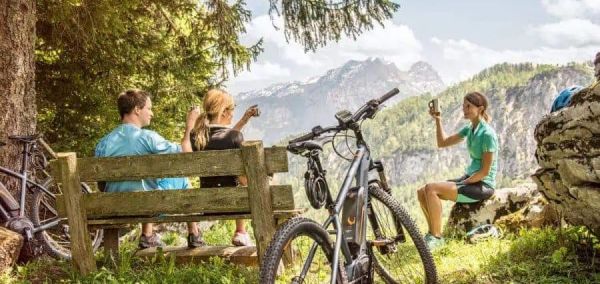 Cykliści odpoczywjący podczas wycieczki rowerowej robią selfie na tle pięknych szczytów Salzburskiego Saalachtalu